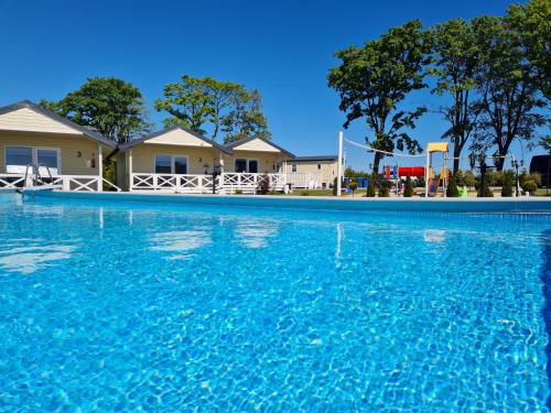 a swimming pool with blue water in front of houses at Holiday Camp Sarbinowo in Sarbinowo