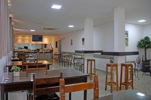 a restaurant with tables and chairs and a bar at Hotel Portela II - Av Principal e a 500m do Thermas dos Laranjais in Olímpia