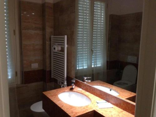 a bathroom with a sink and a toilet and a mirror at Residenza Grand Hotel Riccione in Riccione