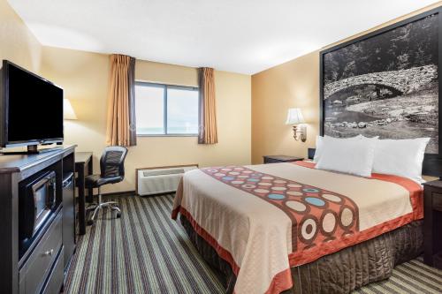 a hotel room with a bed and a flat screen tv at Super 8 by Wyndham Iowa Falls in Iowa Falls