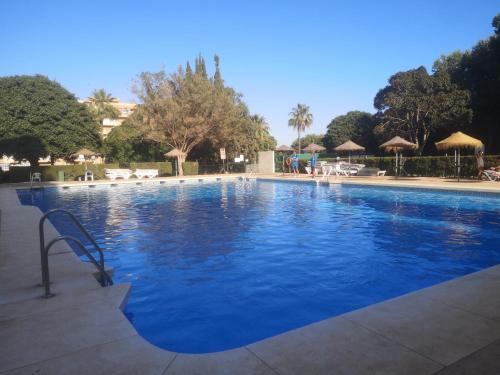 a large blue swimming pool with chairs and umbrellas at Cosy beach suite Agata in Benalmádena