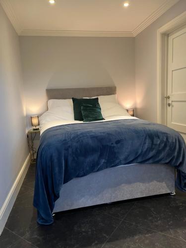 a bed with a blue blanket and two pillows on it at Thistle Lodge - Quiet Garden lodge with off road parking in Hemel Hempstead