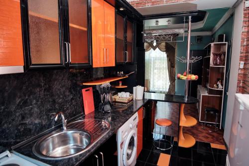 a kitchen with orange and black cabinets and a sink at RO METRO in Gyumri