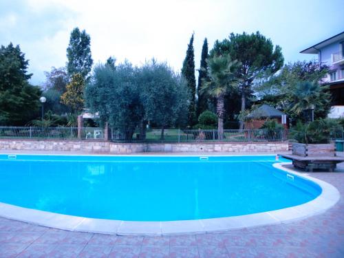a blue swimming pool with a bench and trees at Hotel Miami in Civitella del Tronto