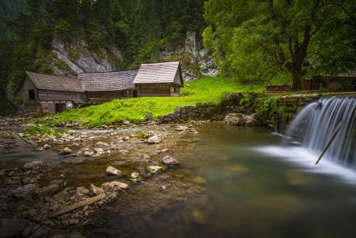 a cabin next to a waterfall next to a river at Liptovský mlyn in Bešeňová