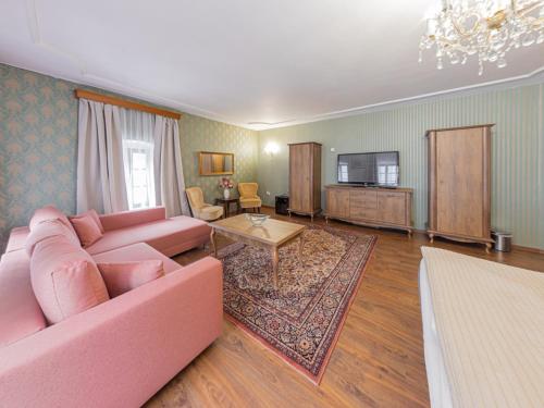 a living room with a pink couch and a tv at Hotel Salamander - Garni in Banská Štiavnica