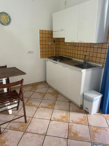 a kitchen with white cabinets and a sink and a table at Casa ISABELLA loc turist br in Lipari
