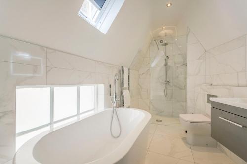 a white bathroom with a tub and a toilet at The Old School Room - The Lace Market in Nottingham