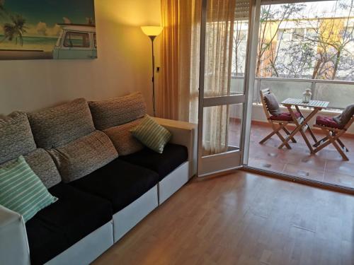 sala de estar con sofá, mesa y sillas en Apartamento Playa Victoria, en Cádiz