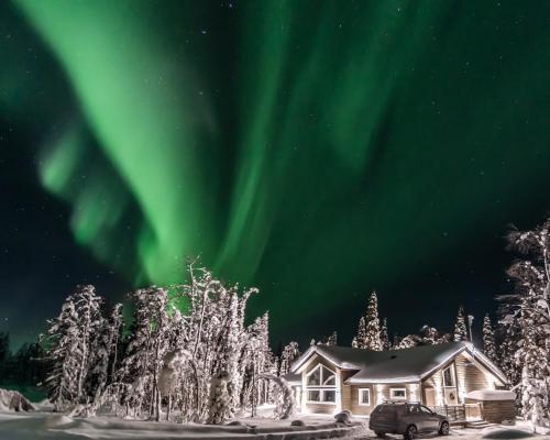 a house under the aurora in the snow at Foxfires Private Boutique Guesthouse in Levi