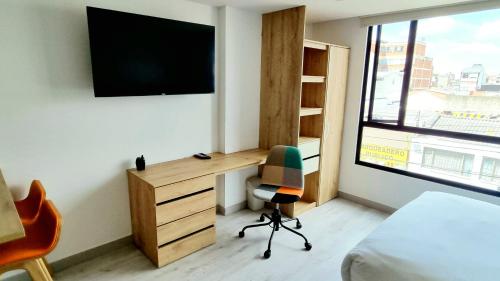 a bedroom with a desk and a chair and a tv at Toscana LOFT - Apartasuites in Bogotá