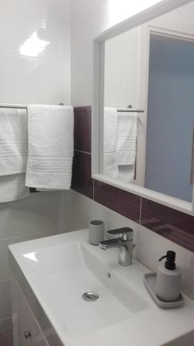 a bathroom with a sink and a mirror and towels at Kalavarda Cosy Home 1 in Kalavárda