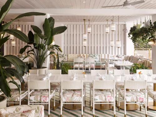 a dining room with white tables and chairs and plants at PGA National Resort in Palm Beach Gardens