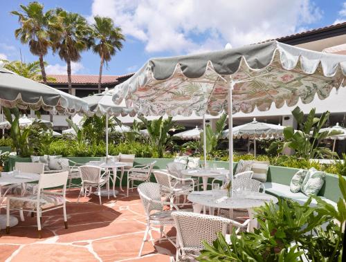 an outdoor patio with tables and chairs and umbrellas at PGA National Resort in Palm Beach Gardens
