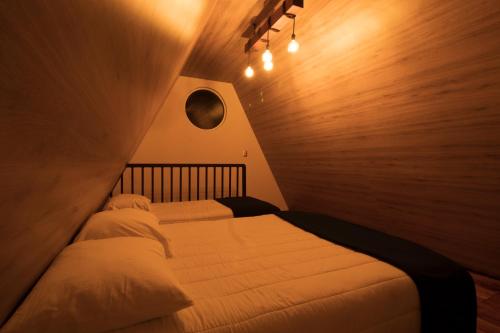 two beds in a small room with white sheets at Villa de los Vientos in Cuetzalán del Progreso
