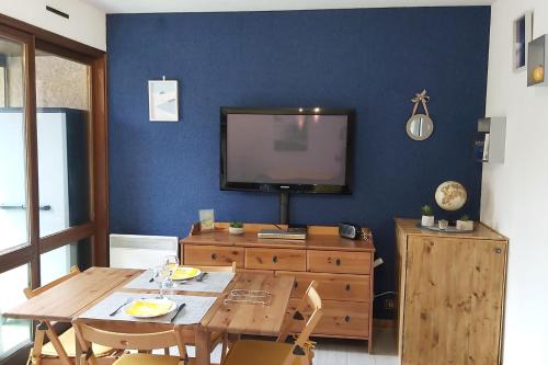 a dining room with a table and a tv on a blue wall at Studio sur parc proche centre et télécabine in Briançon