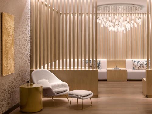 a living room with a white chair and a chandelier at PGA National Resort in Palm Beach Gardens