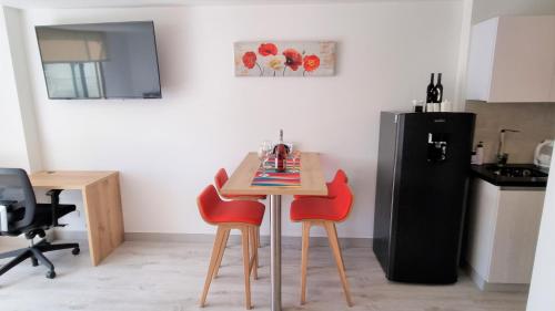 a kitchen with a small table and two red chairs at Toscana LOFT - Apartasuites in Bogotá
