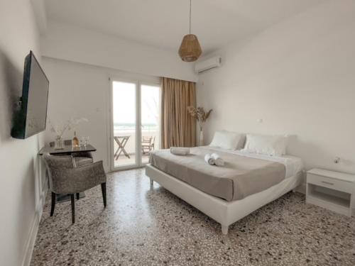 a bedroom with a bed and a desk and a television at TIKI BEACH STUDIOS in Nea Makri