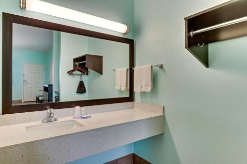 a bathroom with a sink and a large mirror at Island Hotel Port Aransas in Port Aransas