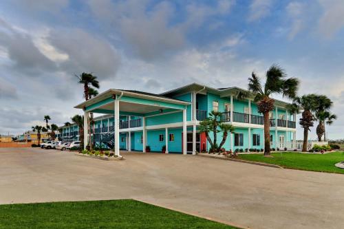 a large blue building with palm trees in front of it at Island Hotel Port Aransas in Port Aransas