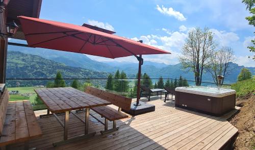 una terraza con bañera de hidromasaje, mesa de picnic y sombrilla en Ruhige Bergvilla in Alleinlage am Mondsee mit Seeblick Bergblick und Whirlpool en Innerschwand