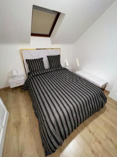 a bedroom with a bed with a black and white striped comforter at Luxury suites maladiere 1 in Dijon