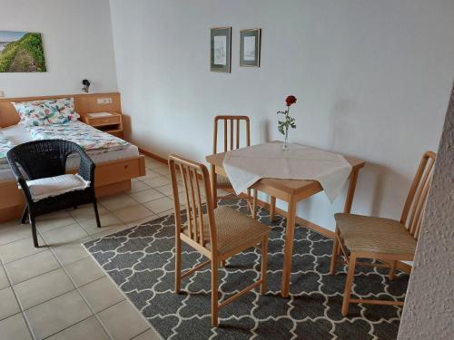 een woonkamer met een tafel en stoelen en een bed bij Gästehaus Annette Hermes-Hoffmann in Trittenheim