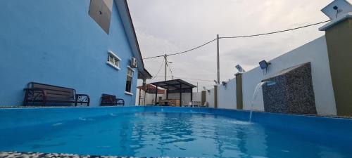 a blue swimming pool on the side of a building at Rest n Splash by Home Stay Cikgu D'Inapan Kijang in Alor Setar
