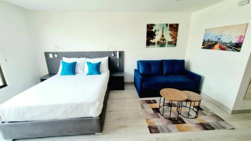 a bedroom with a bed and a blue chair at Toscana LOFT - Apartasuites in Bogotá
