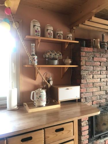 a kitchen with wooden shelves and a brick wall at Domek Panorama in Lipowa