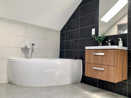 a bathroom with a white tub and a sink at Apartament Penthouse z widokiem na Śnieżkę i prywatnym parkingiem - by SpaceApart in Jelenia Góra