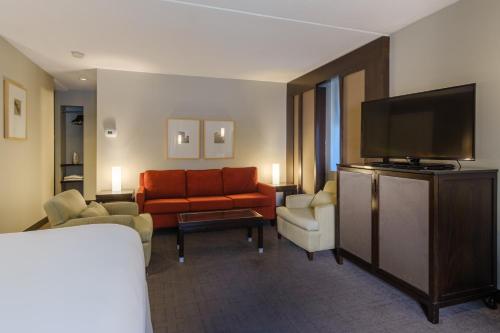 a hotel room with a couch and a flat screen tv at Arc The Hotel in Ottawa