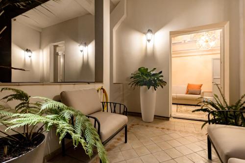 a waiting room with chairs and plants and a mirror at Palazzo Guajana in Trapani