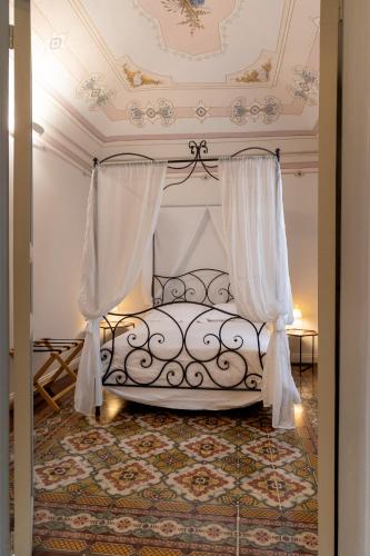 a bedroom with a bed with curtains and a ceiling at Palazzo Guajana in Trapani