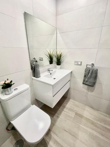 a white bathroom with a toilet and a sink at ISLAND SUITES in Arona