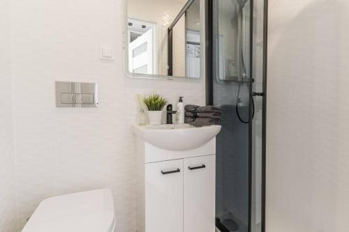 y baño blanco con lavabo y ducha. en Uroczy apartament 2 pokoje - 10 min do morza!, en Gdansk