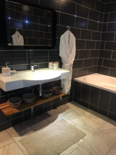 een badkamer met een wastafel, een bad en een spiegel bij La suite cosy de Julie , 2 pièces 3 lits parking privé Résidence Cosyade in Bourbourg