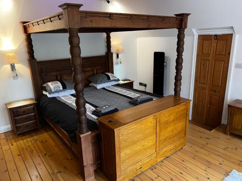 a canopy bed with a wooden frame in a room at Castle House Holiday Home in Chapel en le Frith