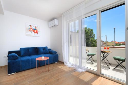 a living room with a blue couch and a large window at Bonaca apartments with terrace and private parking in Kaštela