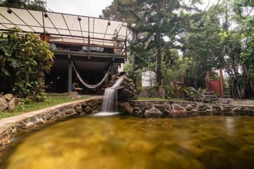 a fountain in a pond in front of a house at Auá Hostel in Petrópolis