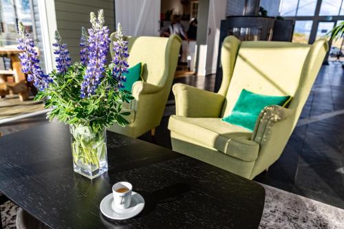 a vase of purple flowers on a table with chairs at Aurora Lodge Hotel in Hvolsvöllur