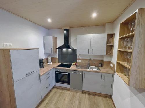 a kitchen with white cabinets and a sink and a stove at Ferienwohnung Isabell in Briedern