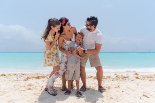 a family posing for a picture on the beach at The Reef Playacar Beach Resort & Spa-Optional All Inclusive in Playa del Carmen