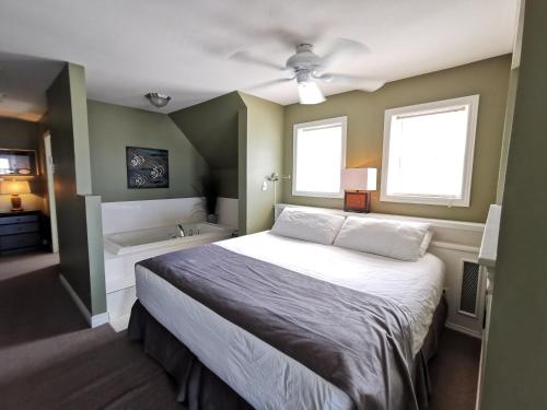 a bedroom with a bed and a sink and a tub at Inn on the Harbour and Telegraph House in Port Stanley