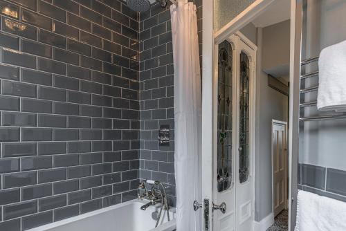 a bath tub in a bathroom with blue tiles at Coastal Cottage: Charming three bedroom cottage with private garden in Ramsgate