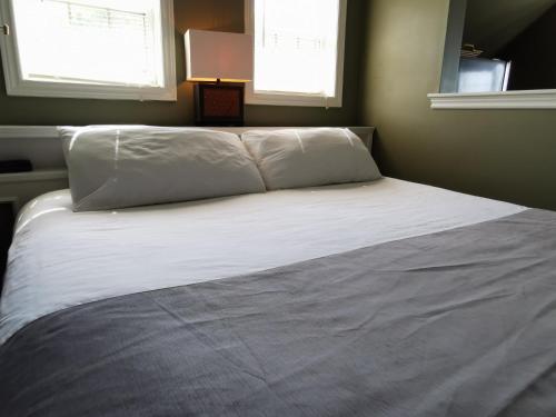 a bed with white sheets and pillows in a bedroom at Inn on the Harbour and Telegraph House in Port Stanley