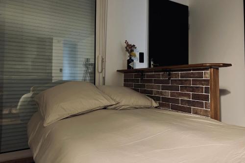 a bed in a bedroom with a brick wall at APPT LANTON PLAGE - PORT 6 Voyageurs in Lanton