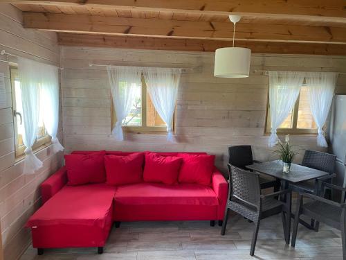 a red couch in a room with a table and windows at Camping Szczecinek Domy Wypoczynkowe in Szczecinek
