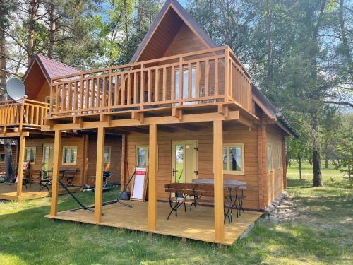 a large wooden cabin with a deck and a table at Camping Szczecinek Domy Wypoczynkowe in Szczecinek